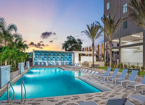 a swimming pool with a bunch of chairs around it at Elements on Third Apartments, Florida