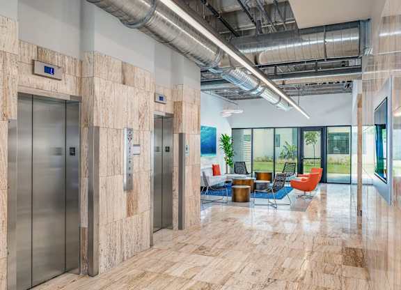 the lobby of a building with elevators and a table and chairs at Elements on Third Apartments, Florida, 33713
