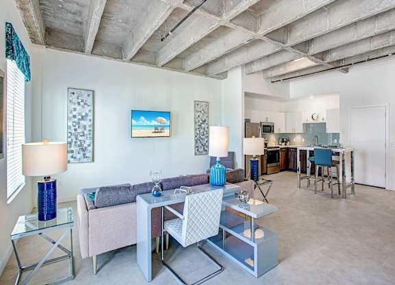 a living room with a couch and tables and a kitchen in the background at Elements on Third Apartments, Florida