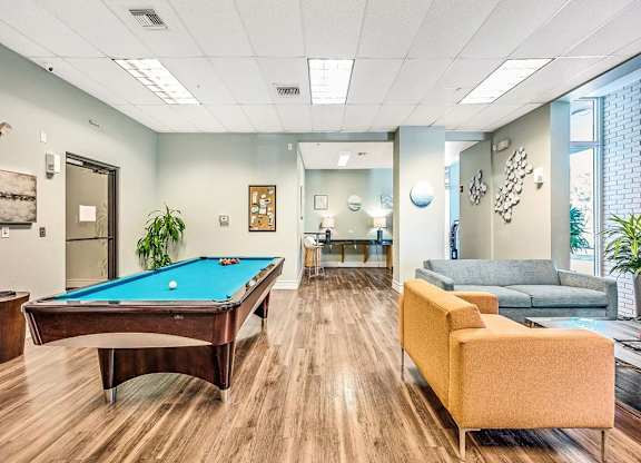 a game room with a pool table and couches at Elements on Third Apartments, St. Petersburg, FL