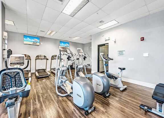a gym with cardio machines and a mirror in the corner at Elements on Third Apartments, St. Petersburg, FL