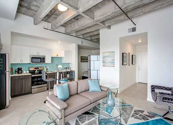 a living room with a couch and a glass table at Elements on Third Apartments, St. Petersburg, FL