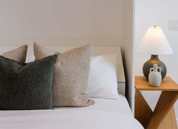 a bed with pillows and a table with a lamp