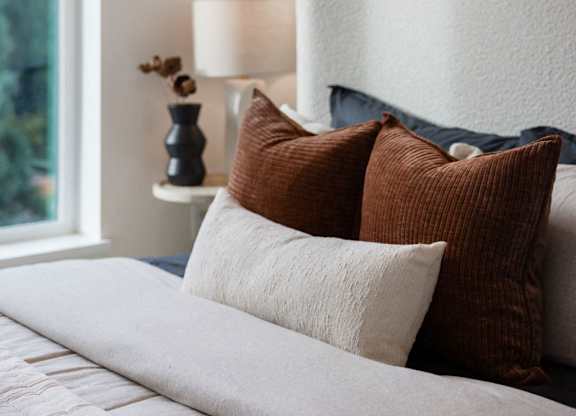 a bed with pillows in a room with a large window