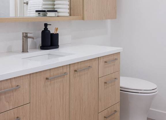 a bathroom with wooden cabinets and a toilet and a mirror