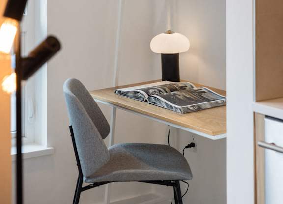 a small desk with a chair and a lamp in a room