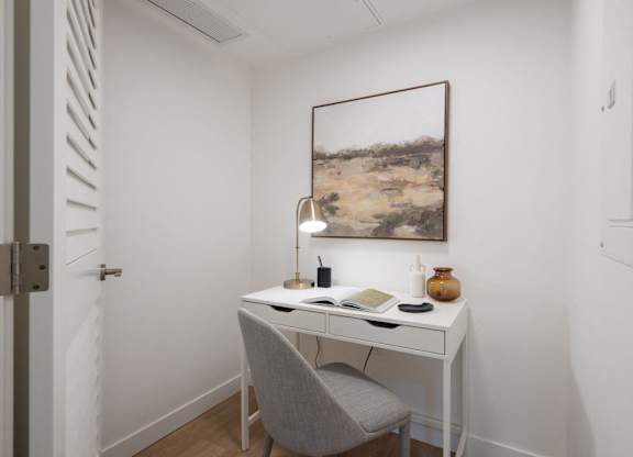 a home office with a desk and a painting on the wall