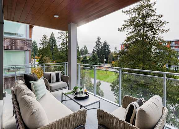 a living room with a couch and chairs on a balcony