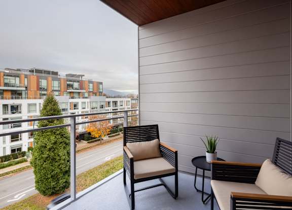 a balcony with two chairs and a table and a city in the background