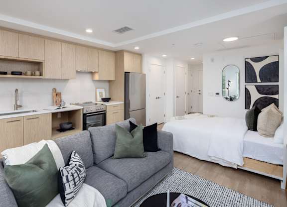 a living room with a couch and a kitchen with a bed