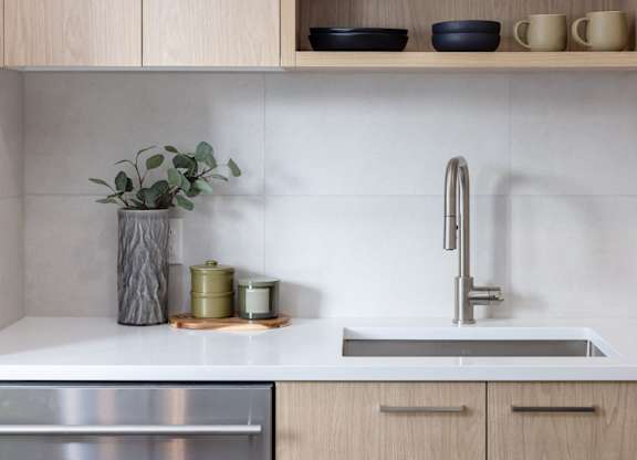 a white kitchen with wooden cabinets and a stainless steel sink