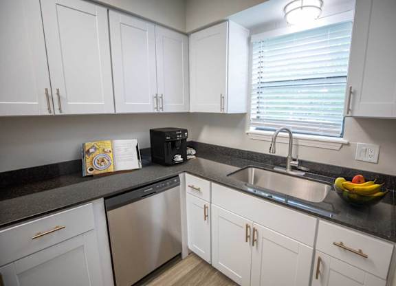 A kitchen with white cabinets and a black countertop.