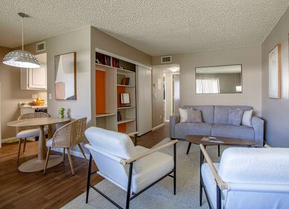 A living room with a grey couch, a white chair and a brown table.