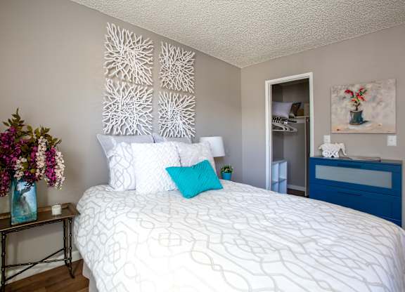 A white bed with a blue pillow and a white wall with a decorative panel.