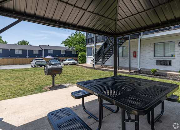 A black table and two black chairs are on a patio.