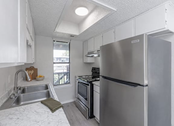 A kitchen with a stainless steel refrigerator, oven, and sink.