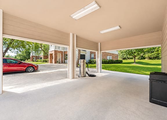A red car is parked in a garage with a black box on the floor.
