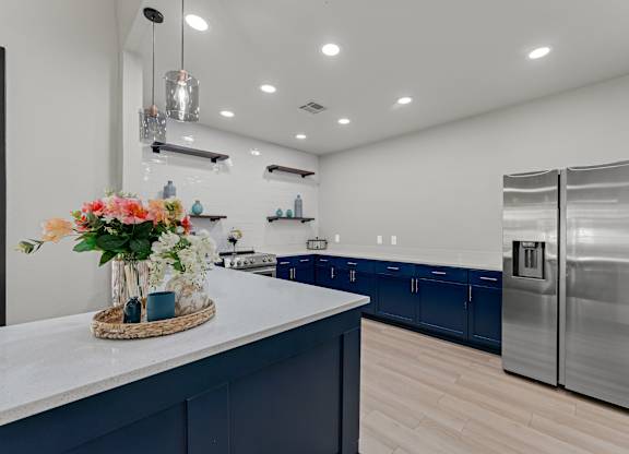A kitchen with a white counter and a vase of flowers on it.