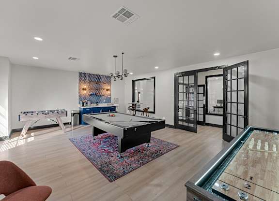 A room with a pool table and a foosball table.