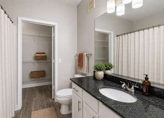 A bathroom with a white toilet, a sink, and a mirror.