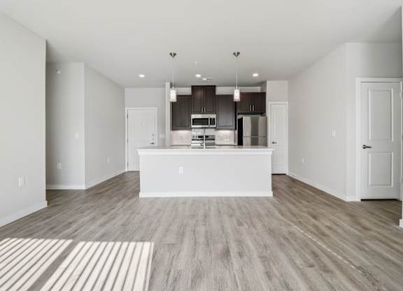 A modern kitchen with a white island and wooden floors.