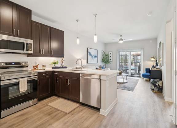 A modern kitchen with dark brown cabinets and stainless steel appliances.