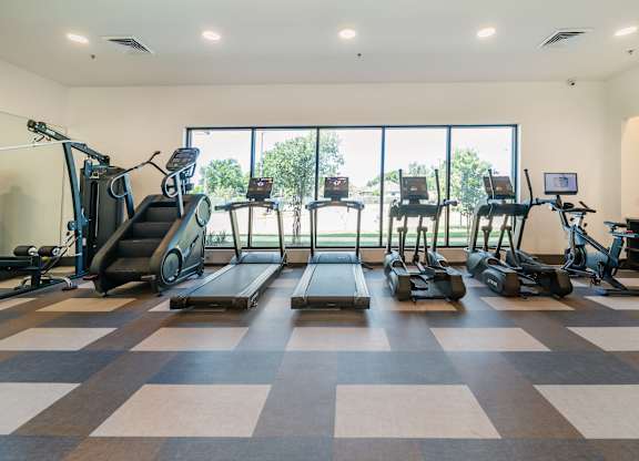 A gym with treadmills, elliptical machines, and a rowing machine.