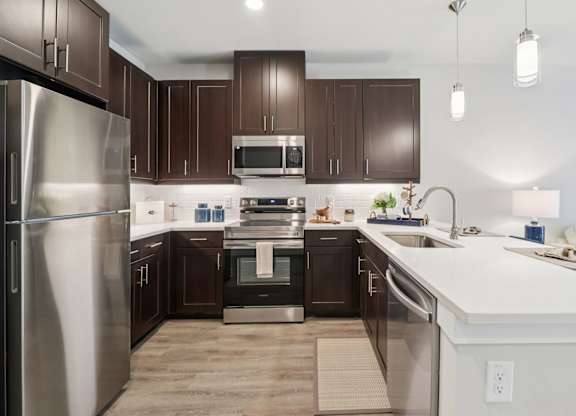 A modern kitchen with dark brown cabinets and stainless steel appliances.
