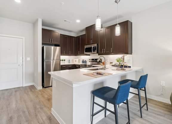 A kitchen with a white island and blue chairs.