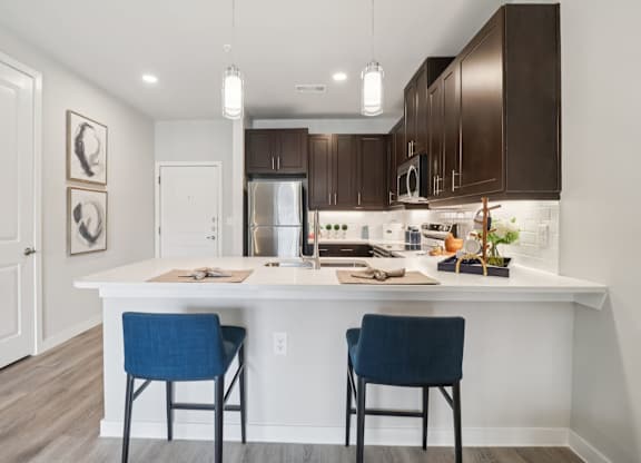 A kitchen with a white island and two blue chairs.