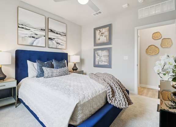 A bedroom with a large bed and a painting on the wall.