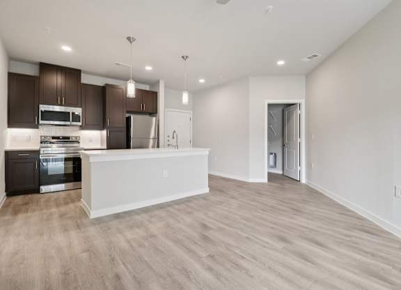 A modern kitchen with dark brown cabinets and stainless steel appliances.