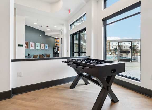 A black pool table in a room with a view of the outside.