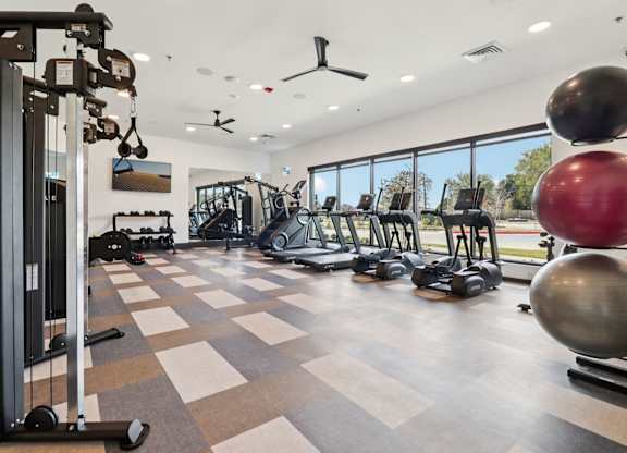 A gym with a variety of equipment including a weight machine, a treadmill, and a rowing machine.