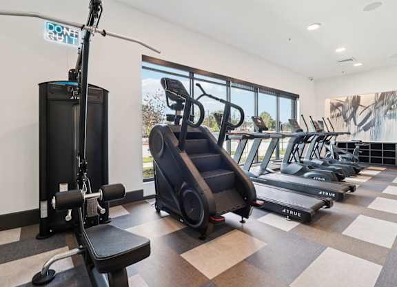 A gym with a variety of equipment including treadmills and weights.