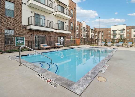 A swimming pool in a residential area surrounded by apartment buildings.