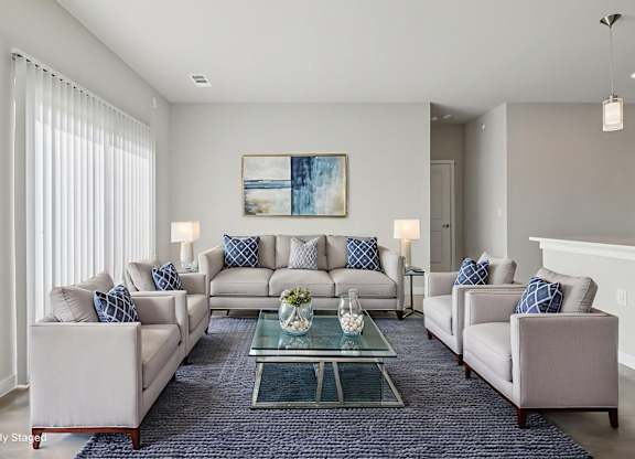 A living room with a large couch, two armchairs, and a coffee table.