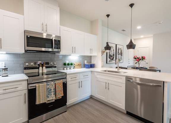 A modern kitchen with white cabinets and stainless steel appliances.