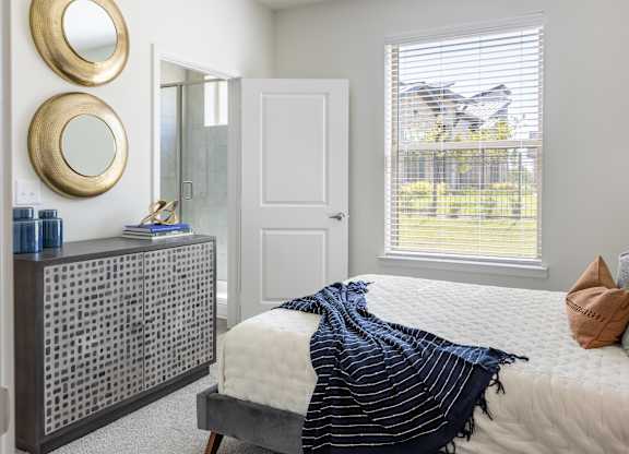 A bedroom with a bed, a dresser, and two round mirrors on the wall.
