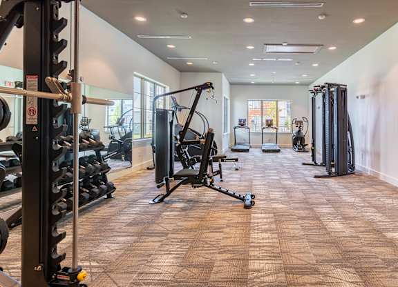 A gym with a variety of equipment including weights and cardio machines.