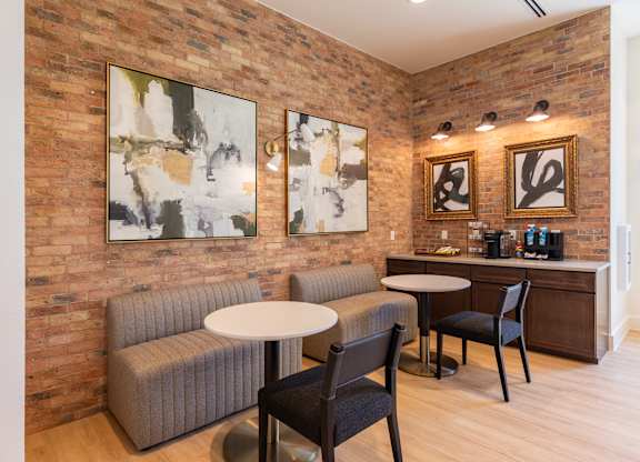 A room with a brick wall and a white table with two chairs.