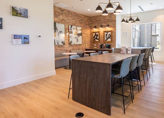 A room with a long table and chairs with a brick wall behind it.