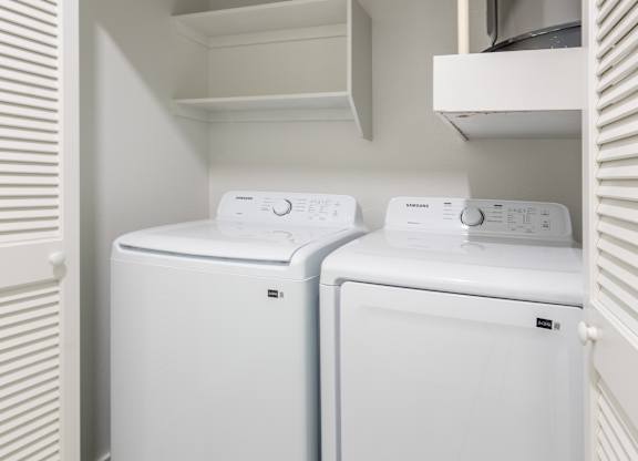 Two white front loading washing machines in a small laundry room.
