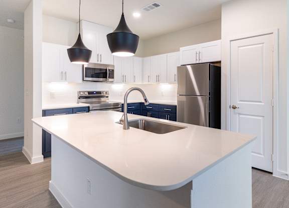 A modern kitchen with a large island and stainless steel appliances.