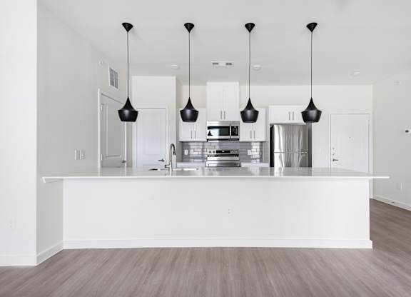 A modern kitchen with a white island and pendant lights.