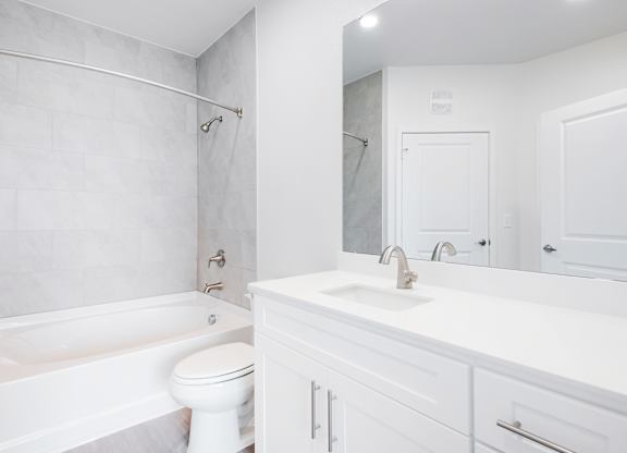 A white bathroom with a toilet, sink, and bathtub.