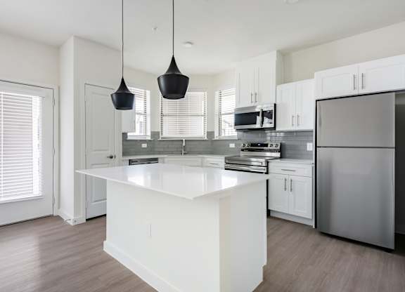 A modern kitchen with a white island and stainless steel appliances.