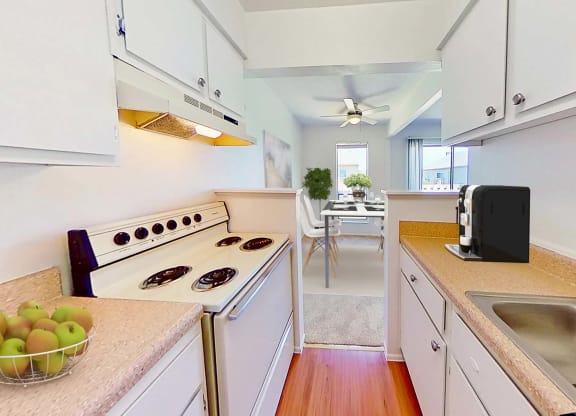 a kitchen with a stove and a bowl of apples