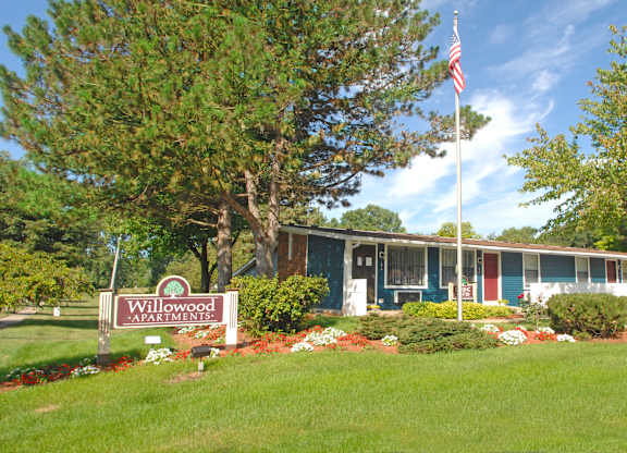 A sign that says Willowood Apartments is in front of a building.