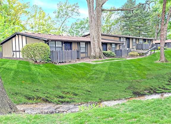 A grassy area in front of a building with trees.